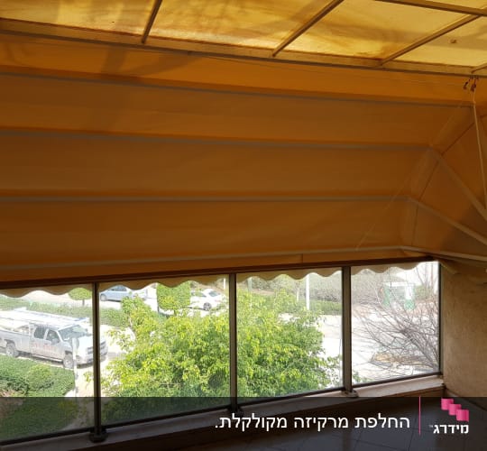 סוכך מרקיזה מתקפל בצבע צהוב מותקן במרפסת דירה